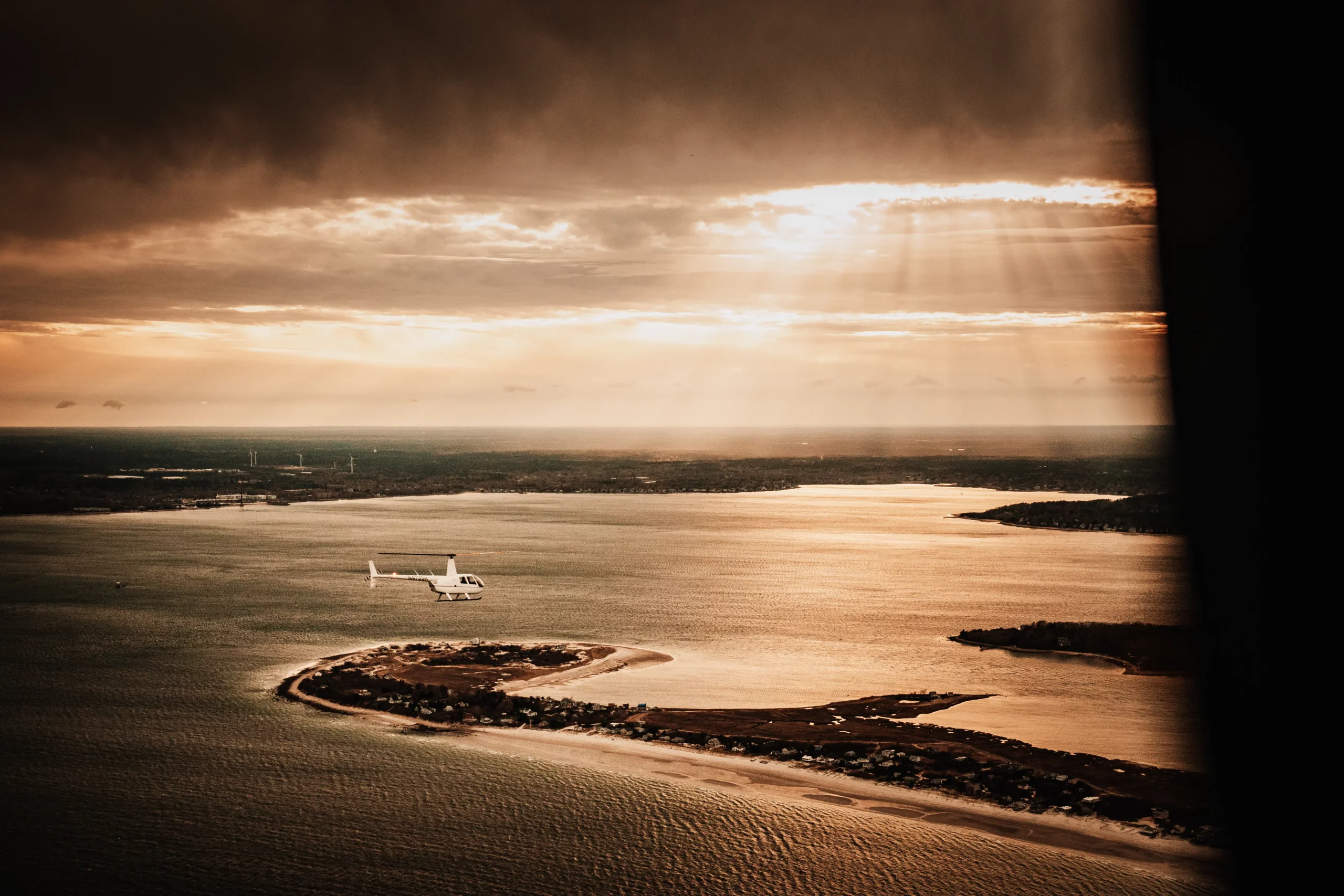 helicopter-flying-past-beautiful-sunrays-over-boston-harbor-islands-coastliine