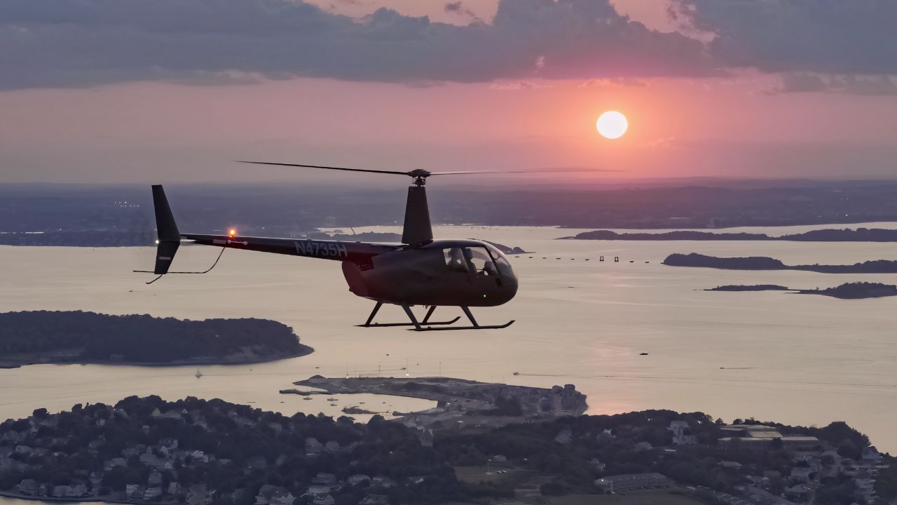 a helicopter flying above Boston at sunset