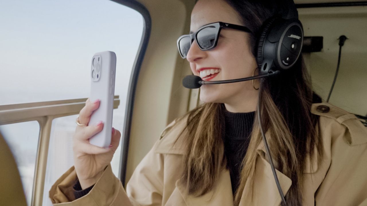 a woman smiles while taking a photo on a helicopter tour