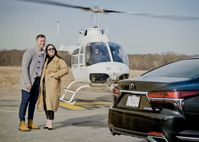man and woman stand in front of a helicopter