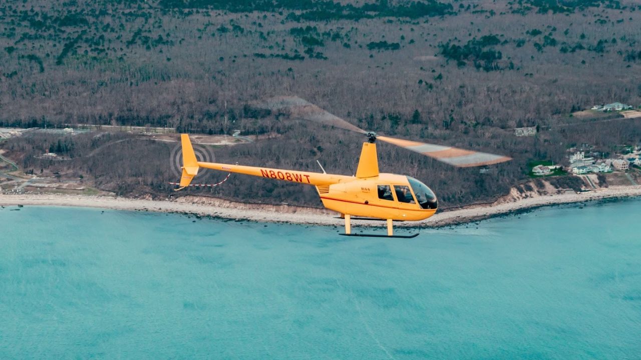 Private helicopter flying above the blue ocean during a Cape Cod day charter service with scenic coastal views below