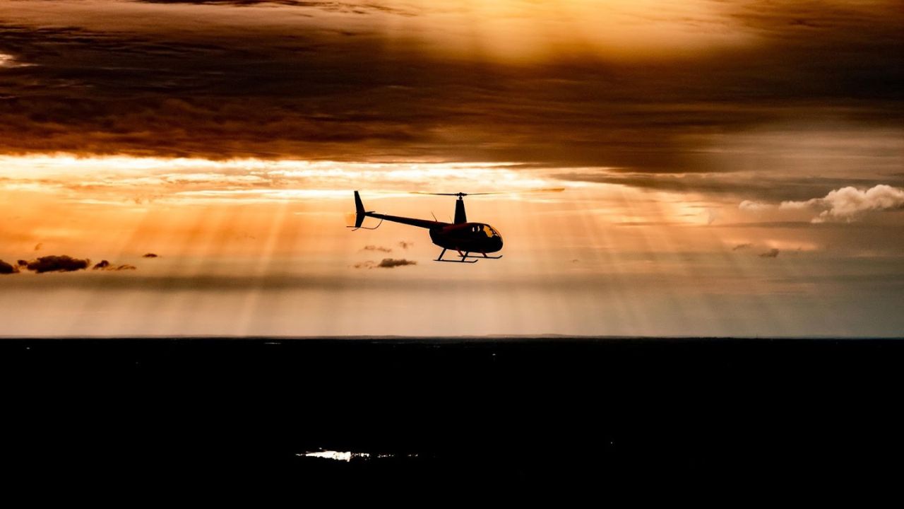 Scenic evening view of a helicopter flying against a warm sunset sky