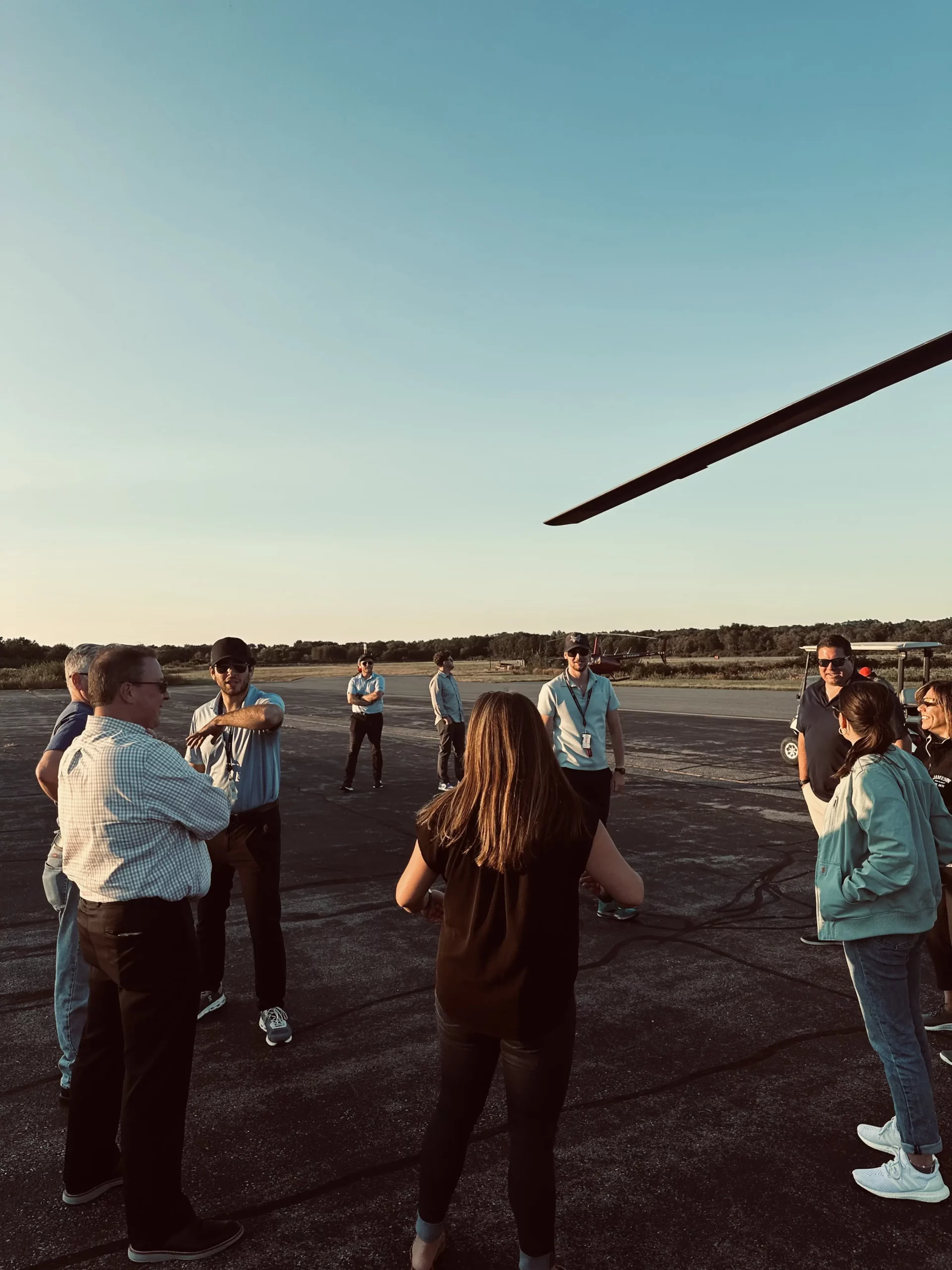 Group of people standing in a circle near a helicopter for a team activity