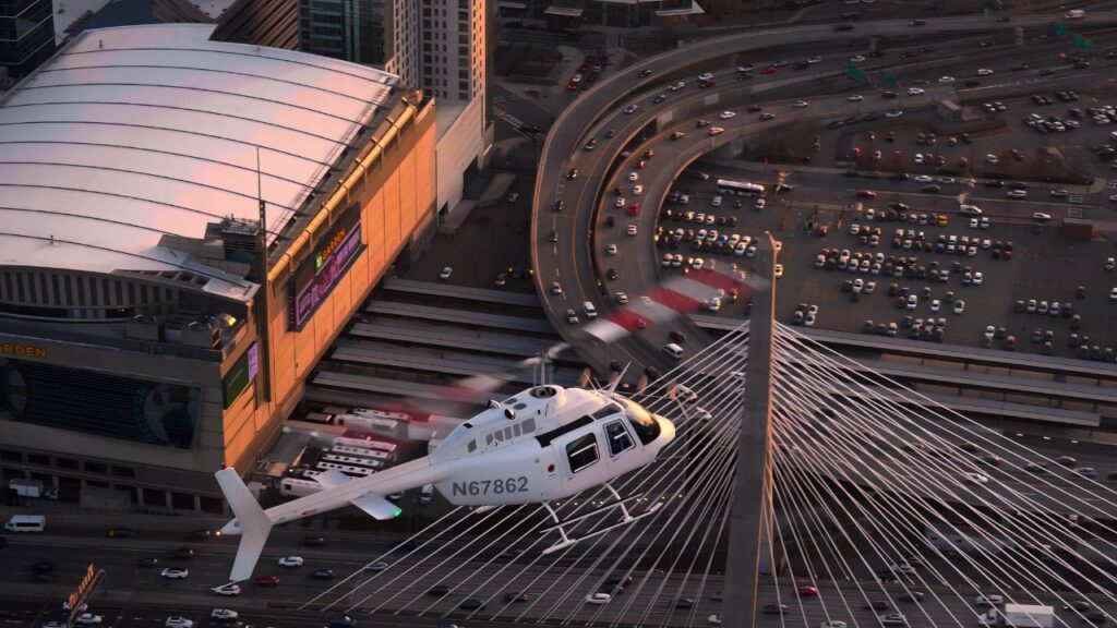 Helicopter flying over a city bridge above heavy highway traffic at sunset